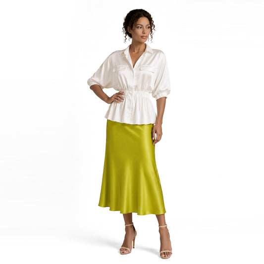 Full-length view of a woman wearing a lime green satin midi skirt with a white peplum blouse and nude heels