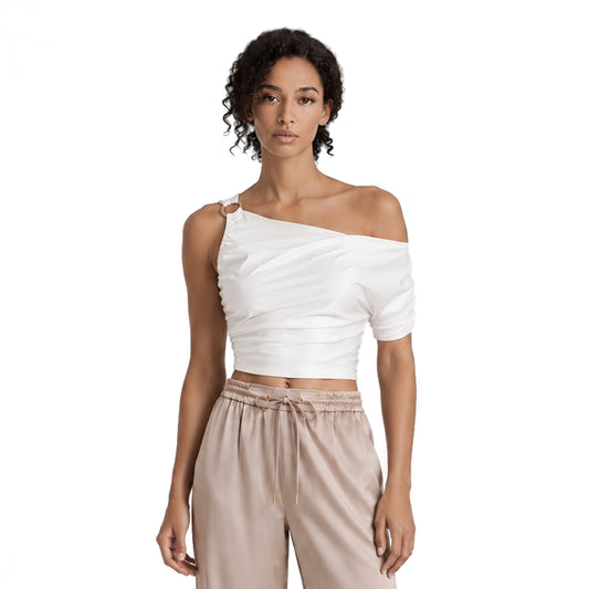 Model wearing a white shimmer one shoulder crop top with an asymmetric neckline, ruched fabric and gold-tone ring detail
